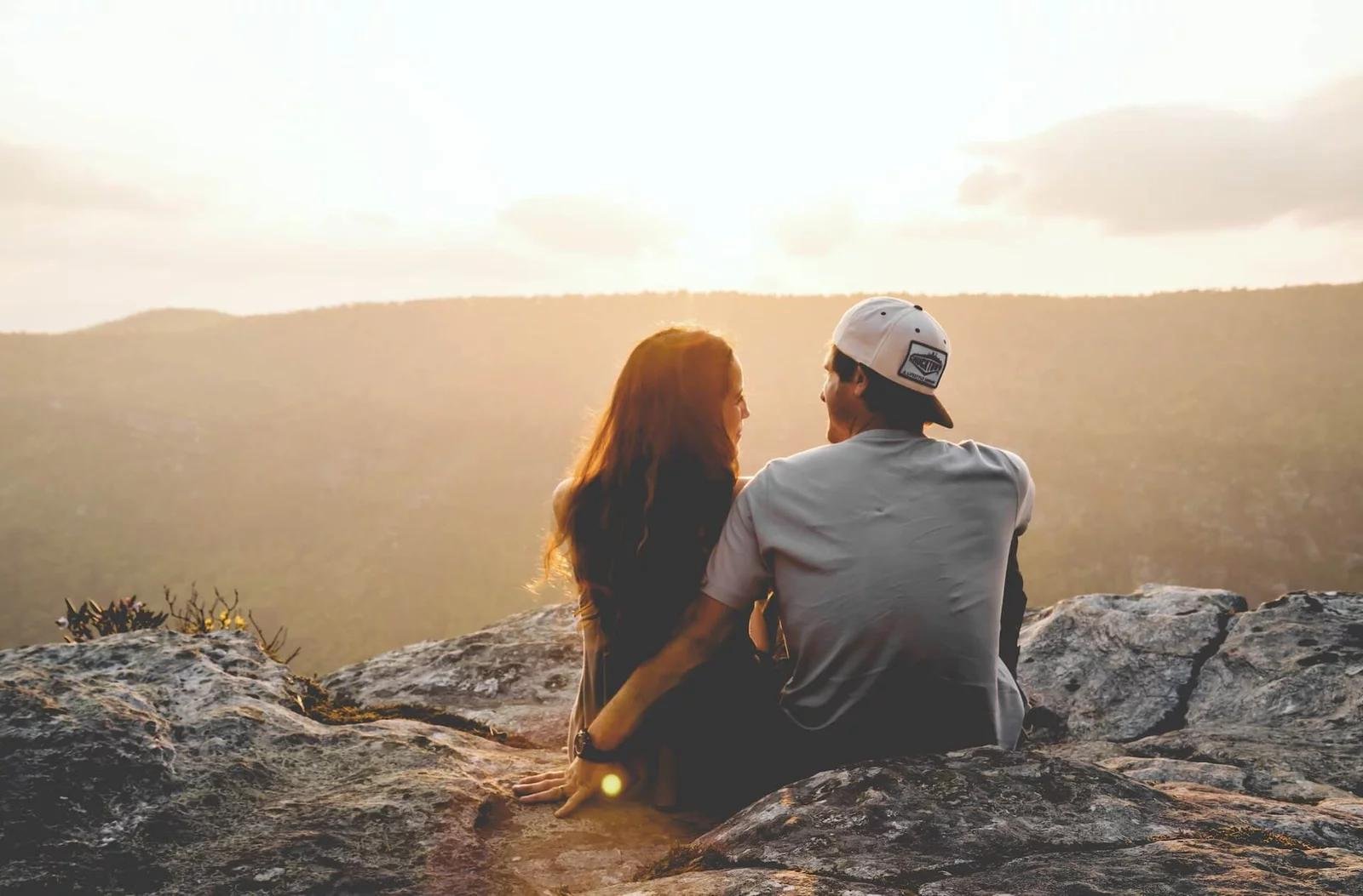 a man and woman sat in nature watching the sunset