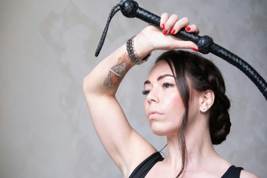a woman holding a black leather flogger